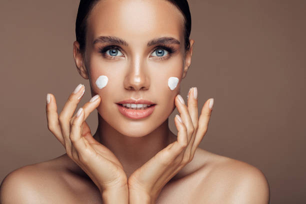 istock Beautiful woman applying cream on her face 1180487068