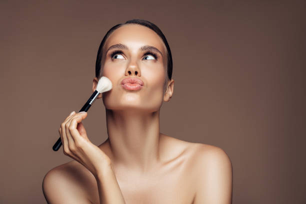 beautiful young woman applying foundation powder - brushing women make up ceremonial makeup imagens e fotografias de stock