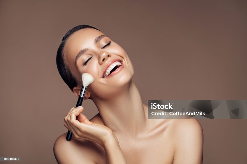Beautiful young woman applying foundation powder Make-Up Stock Photo