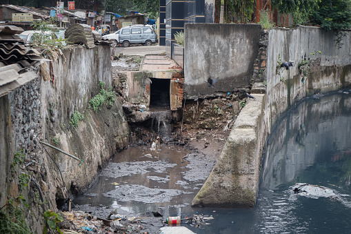 Open sewage gutter running through busy residential location in one of Mumbai's suburbs slum area.Open sewage poses health hazards to local population and risk of drowning during monsoon season