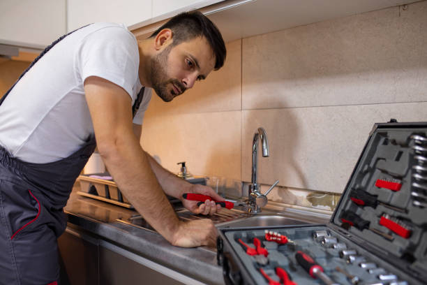 istock Handsome plumber repairing sink pipes in kitchen. 1180493096