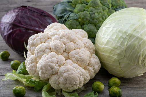 Cauliflower, purple cabbage, broccoli, brussels sprouts and  white cabbage on a wooden background. Rustic style. Selective focus.