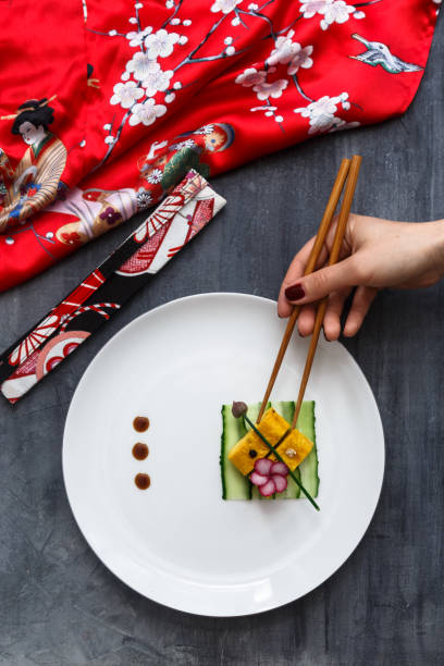 Hand with chopstiks taking a piece of tamagoyaki