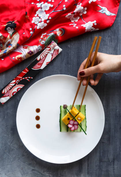 Hand with chopstiks taking a piece of tamagoyaki