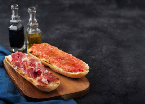 Spanish tomato and ham toast, traditional breakfast or lunch Spanish tomato and jamon toast, traditional breakfast or lunch on black background with copy space spanish breakfast stock pictures, royalty-free photos & images