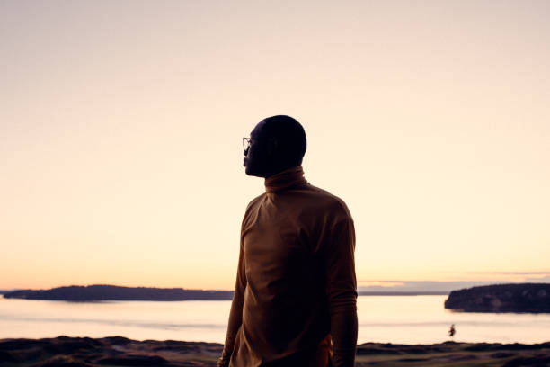 Portrait of Young Man at Sunset A young African American looks out over a body of water at sunset, planning and dreaming of what his future holds. puget sound photos stock pictures, royalty-free photos & images