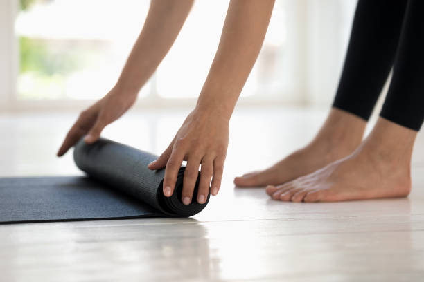 istock Woman practicing yoga, rolling black mat side view close up 1180509550