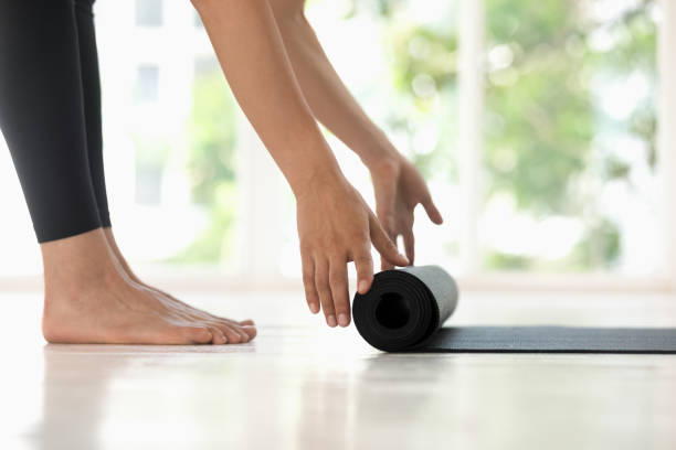 istock Young woman rolling black yoga mat side view close up 1180509553