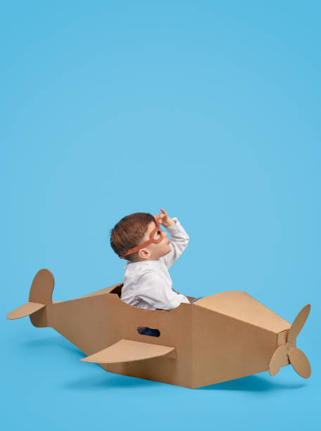 istock Joyful boy playing with cardboard airplane and exploring sky 1180509724