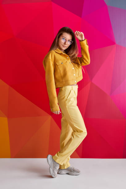 Beautiful woman lying on side in yellow dress front of yellow background