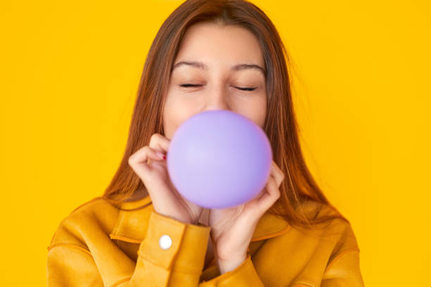 istock Young female blowing balloon with closed eyes 1180509870