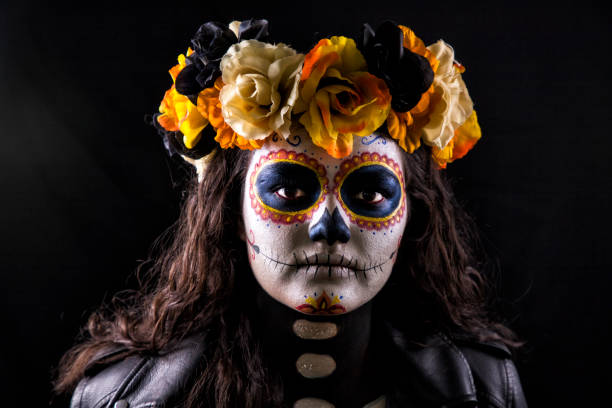Copy space shot of beautiful mid adult woman wearing a Halloween costume and a sugar skull make up while holding a staff with a gipsy skull. She is looking at camera with a slight smile