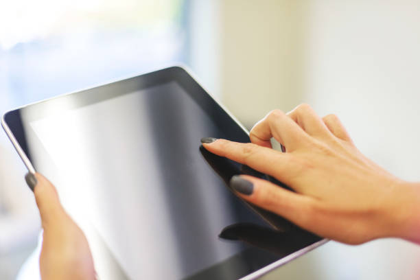 istock Female hands using digital tablet in bright friendly backlit by natural window light office setting completing paperwork and working with technology and enjoying working together as professional advisor and client in Western Colorado 1180519396