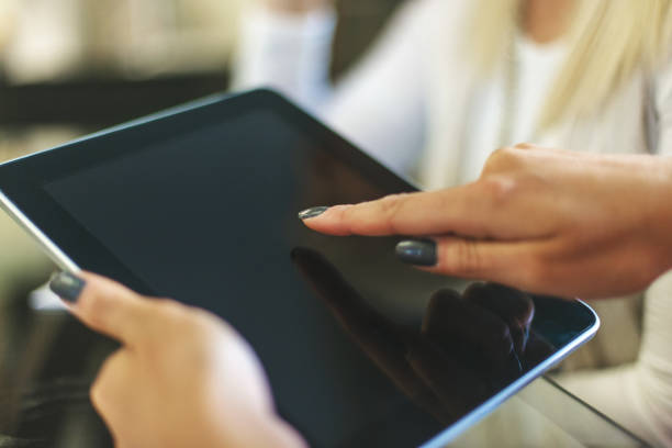 istock Female hands using digital tablet in bright friendly backlit by natural window light office setting completing paperwork and working with technology and enjoying working together as professional advisor and client in Western Colorado 1180519414