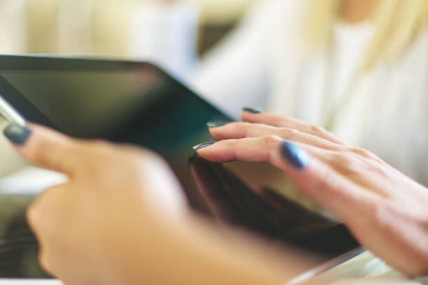 istock Female hands using digital tablet in bright friendly backlit by natural window light office setting completing paperwork and working with technology and enjoying working together as professional advisor and client in Western Colorado 1180519416
