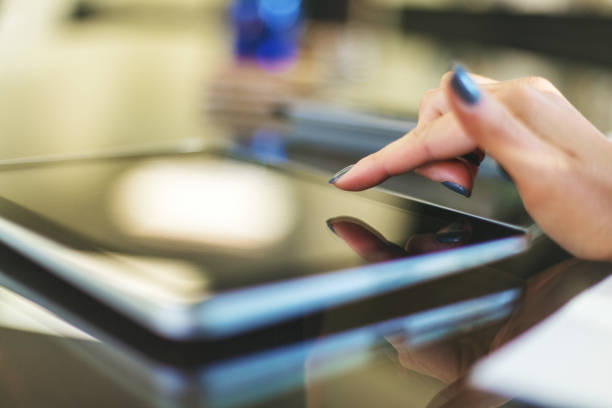 istock Female hands using digital tablet in bright friendly backlit by natural window light office setting completing paperwork and working with technology and enjoying working together as professional advisor and client in Western Colorado 1180519973