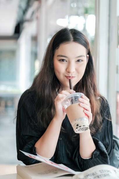 Charming Asian woman sitting drinking pearl milk tea happily. Charming Asian woman sitting drinking pearl milk tea happily. bubble tea photos stock pictures, royalty-free photos & images