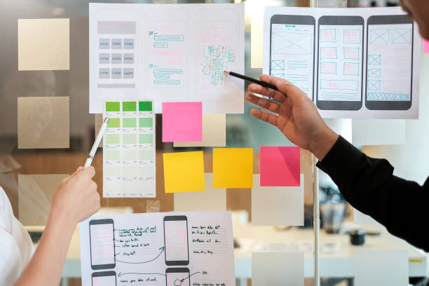 Designer Team Creative Ideas Website Designers draw outlines and develop applications on smartphones. - Project Planning Stock Photos and Images