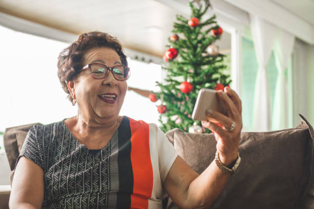 grand-mère recevant le message de noel par le téléphone intelligent - grandmother women one person senior adult photos et images de collection