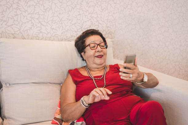 istock Matura woman using mobile phone on the sofa 1180524520