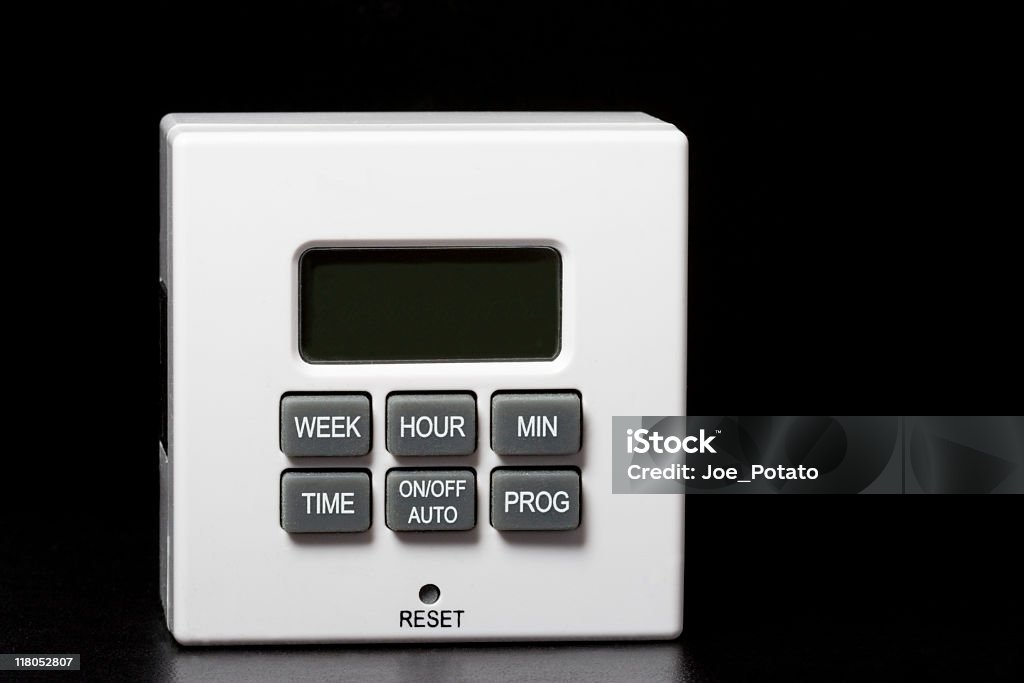 Timer White plug-in timer for electrical items. Black background Mainly used for turning lamps and lights on and off. Horizontal. Color Image Stock Photo