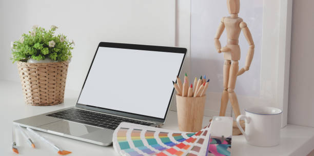 istock Modern artist creative studio with blank screen laptop computer, colour swatches and office supplies 1180529700