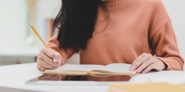 istock Close-up view of young female working on her project while writing her idea concepts on notebook 1180530422