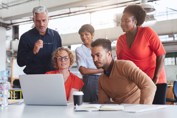 istock Diverse businesspeople using a laptop together in an office 1180531739