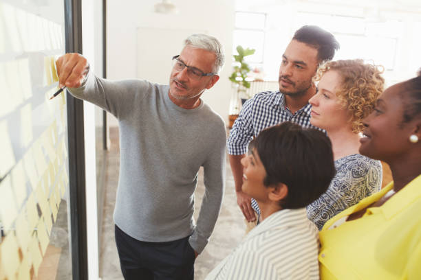 diverse businesspeople brainstorming with adhesive notes in a meeting - flow chart fotos imagens e fotografias de stock