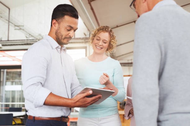 istock Diverse businesspeople smiling while working together on a digital tablet 1180536759