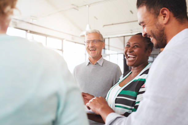 istock Laughing group of diverse businesspeople going over paperwork together 1180536931