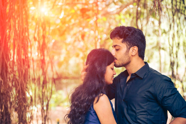 istock Young man kissing his girlfriend on her forehead 1180537742