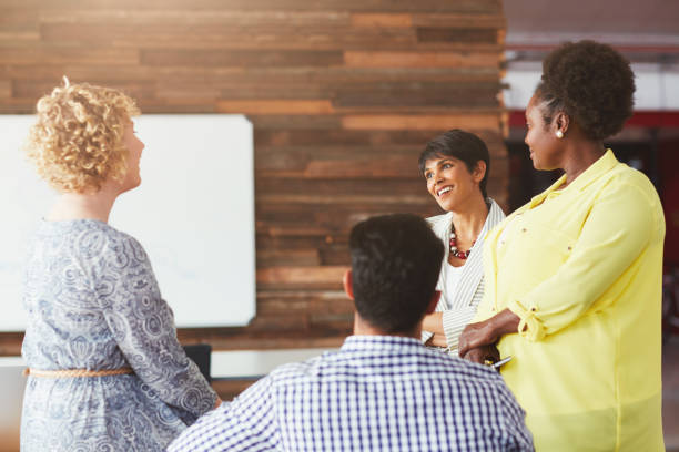 istock Businesspeople smiling and talking together in a bright modern office 1180538281