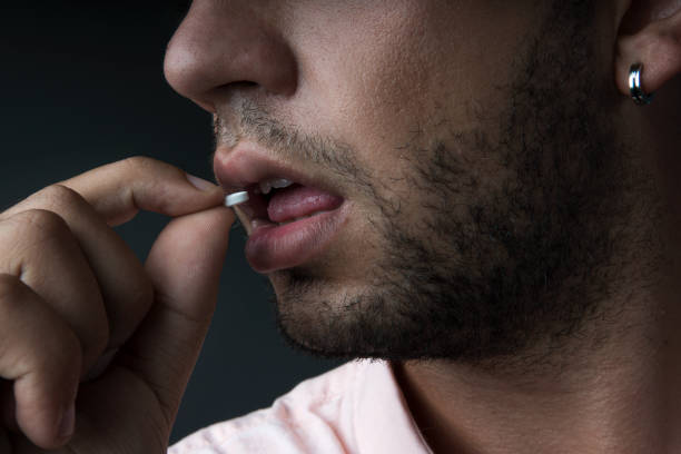 istock Close up image of young man drinking round white pill 1180548443