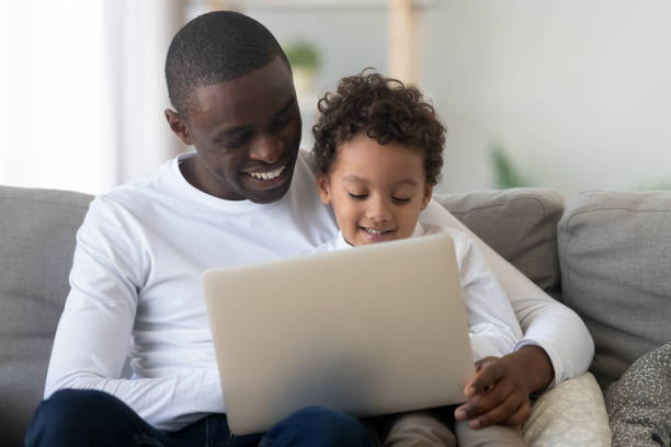 istock Cute kid son learning using laptop with happy black dad 1180549260
