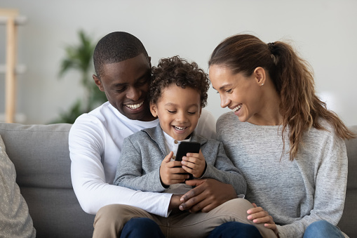 Padres africanos africanos con hijo hijo riendo usando el teléfono photo