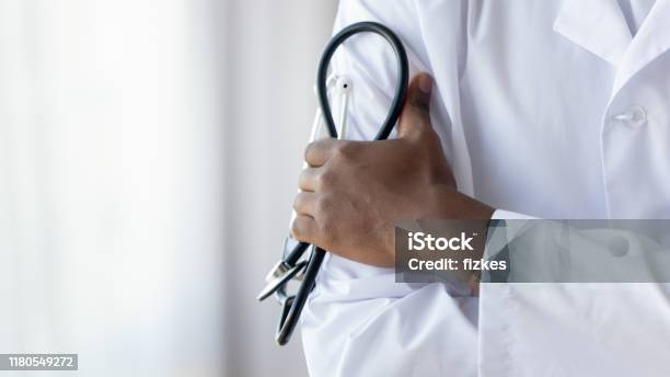 Male African Doctor Wear Medical Coat Holding Stethoscope Close Up Stock Photo - Download Image Now
