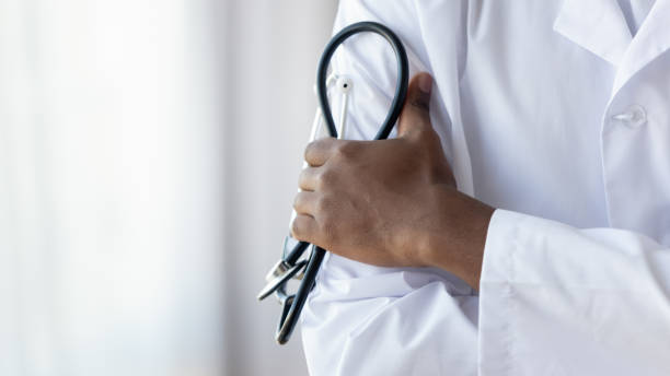 male african doctor wear medical coat holding stethoscope, close up - médico geral imagens e fotografias de stock