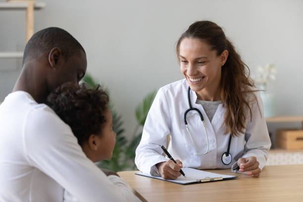 istock Smiling female doctor listen cute african boy make notes 1180549283