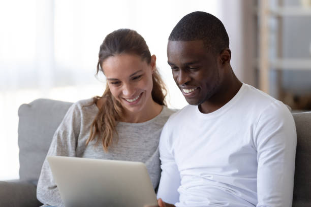 istock Happy mixed race young couple using laptop looking at screen 1180549304