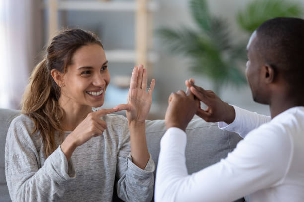 uśmiechnięta mieszana para etniczna rozmawiająca z językiem ręki palca znakowego - message communication sign african descent zdjęcia i obrazy z banku zdjęć