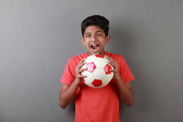 boy holds a soccer ball and screams - facial expression child asia asian and indian ethnicities imagens e fotografias de stock