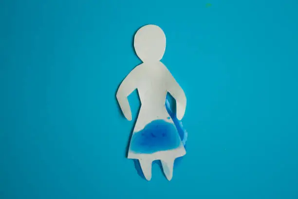 Urinary incontinence concept. Wet paper person. Blue background