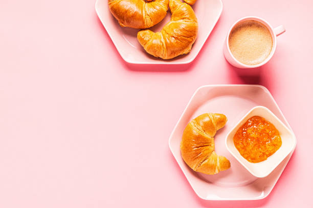 istock Coffee and croissants for breakfast on a pink background 1180555521