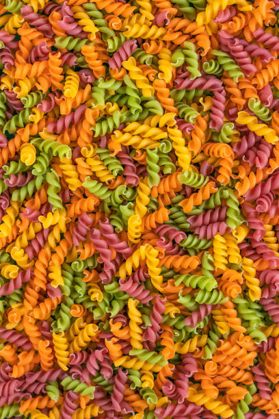 Abstract texture of colorful pasta. Pattern of macaroni. Bright multicolor background. Uncooked colored noodles.