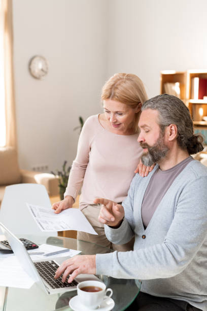 istock Mature husband and wife discussing information on laptop display 1180558808