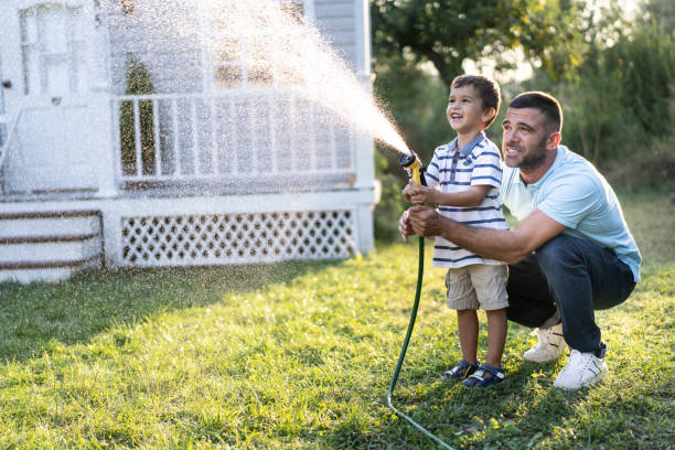 istock Father splashing water and having fun with son on back yard 1180560219