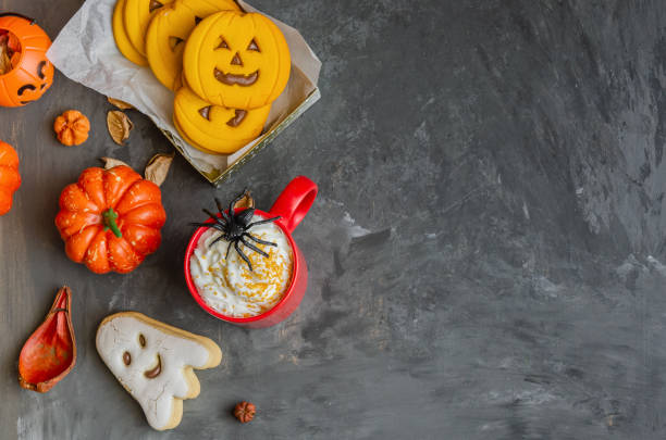 istock Happy Halloween background with copy space. Red mug with traditional punch, different cookies in shape of scary face, ghost  and spider, pumpkins and dry leaves. 1180560338