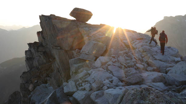 escursione alpinisti lungo la vetta rocciosa all'alba - exploration mountain teamwork mountain peak foto e immagini stock