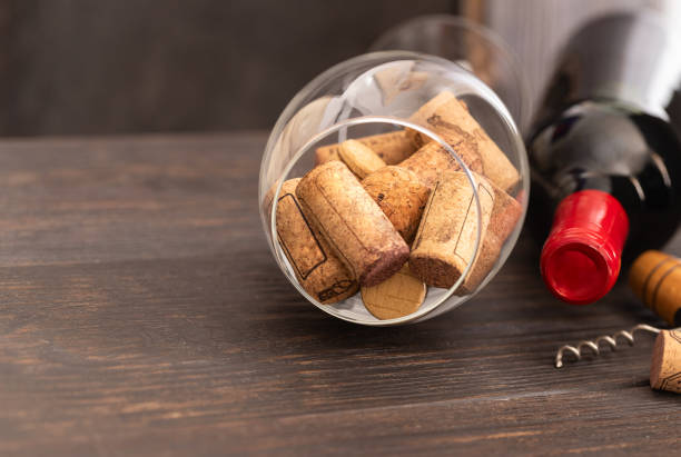 istock Red wine bottle, wine glass with wine corks and  corkscrew on wooden table. Drinking wine concept. 1180561504